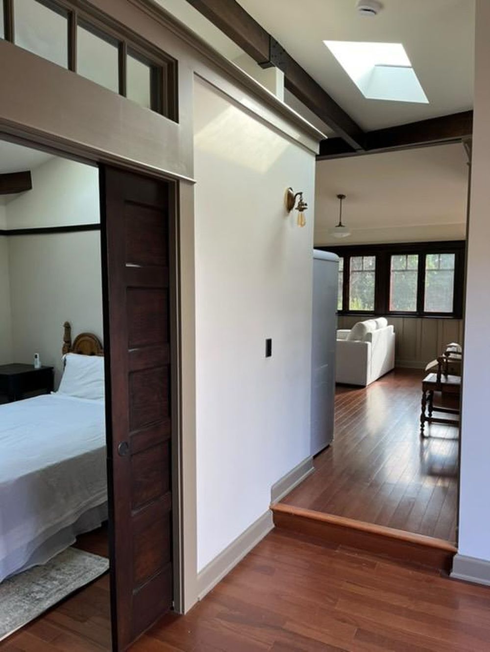 Craftsman ADU interior with skylight, exposed beam, and dark stained pocket door